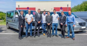 Équipe au complet des pompes funèbres et marbrerie posant devant les véhicules professionnels